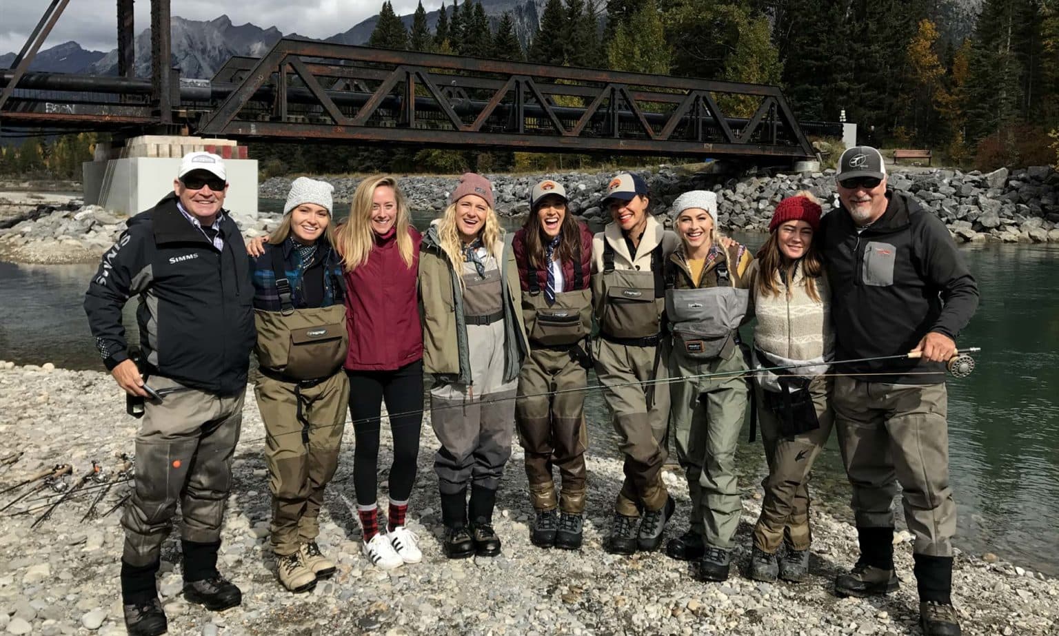 group of people fly fishing on the bow river in canmore with engine bridge in background 